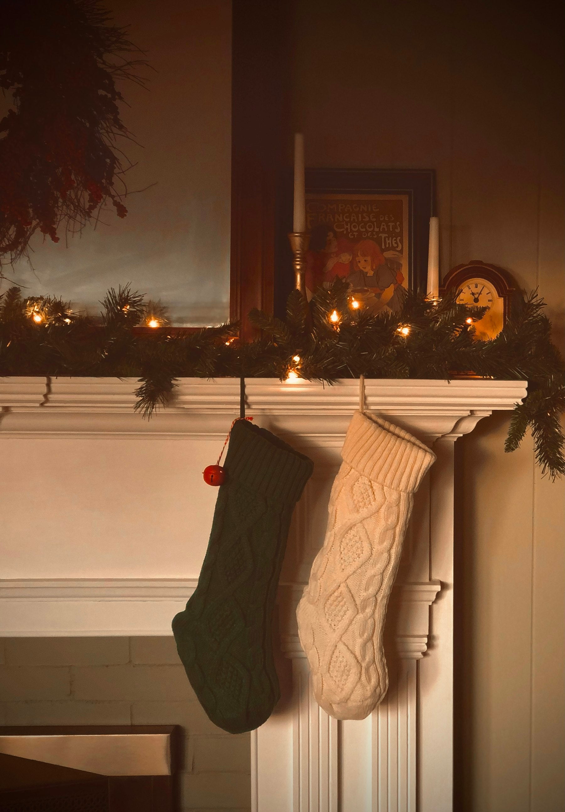 Camino decorato per Natale con ghirlanda, luci calde e calze in maglia